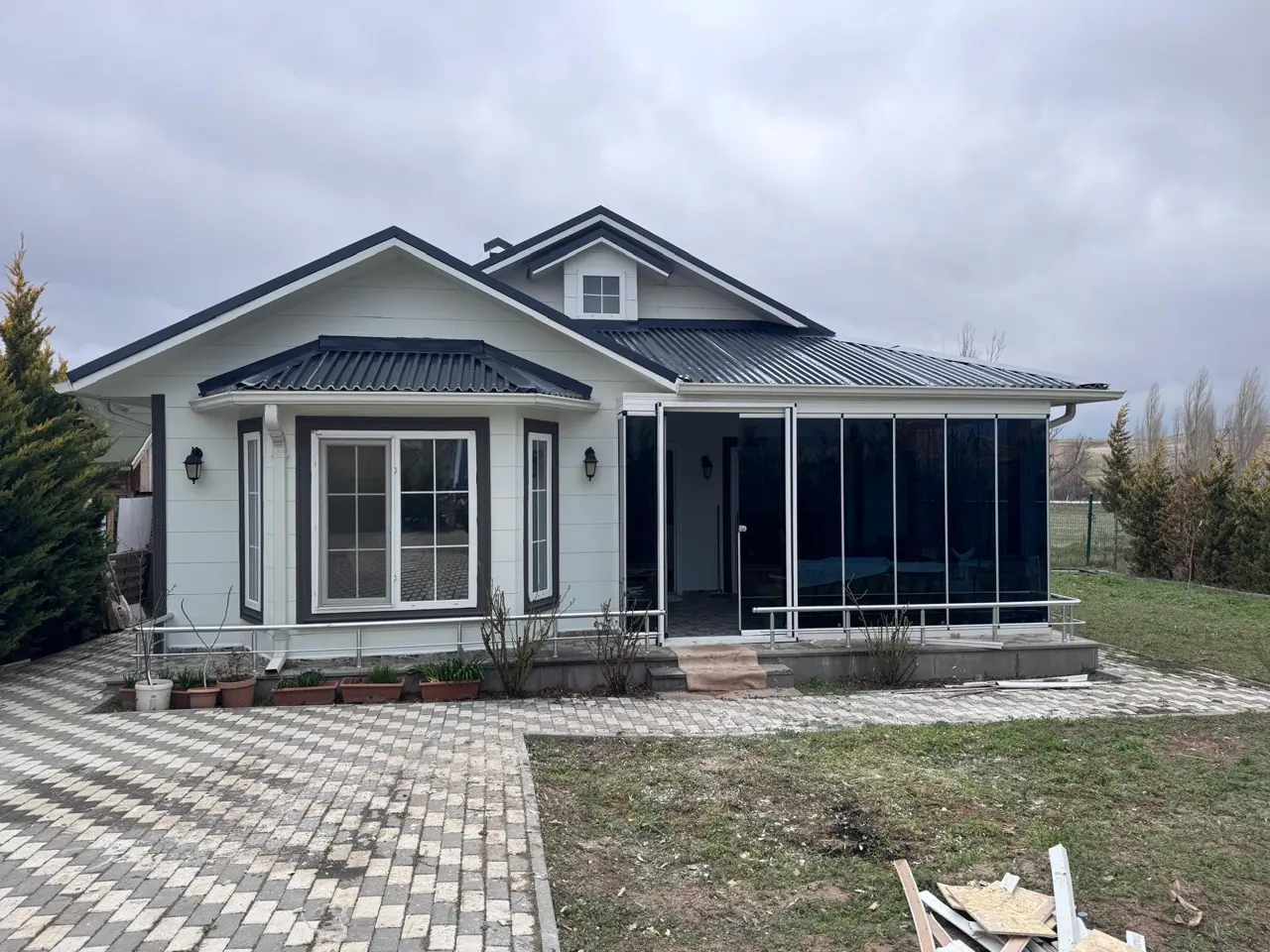 100 m² Çelik Ev: gri ön cephe ve camlı veranda